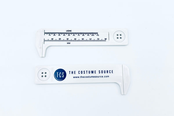 Two white plastic button gauges with TCS logo printed on it 