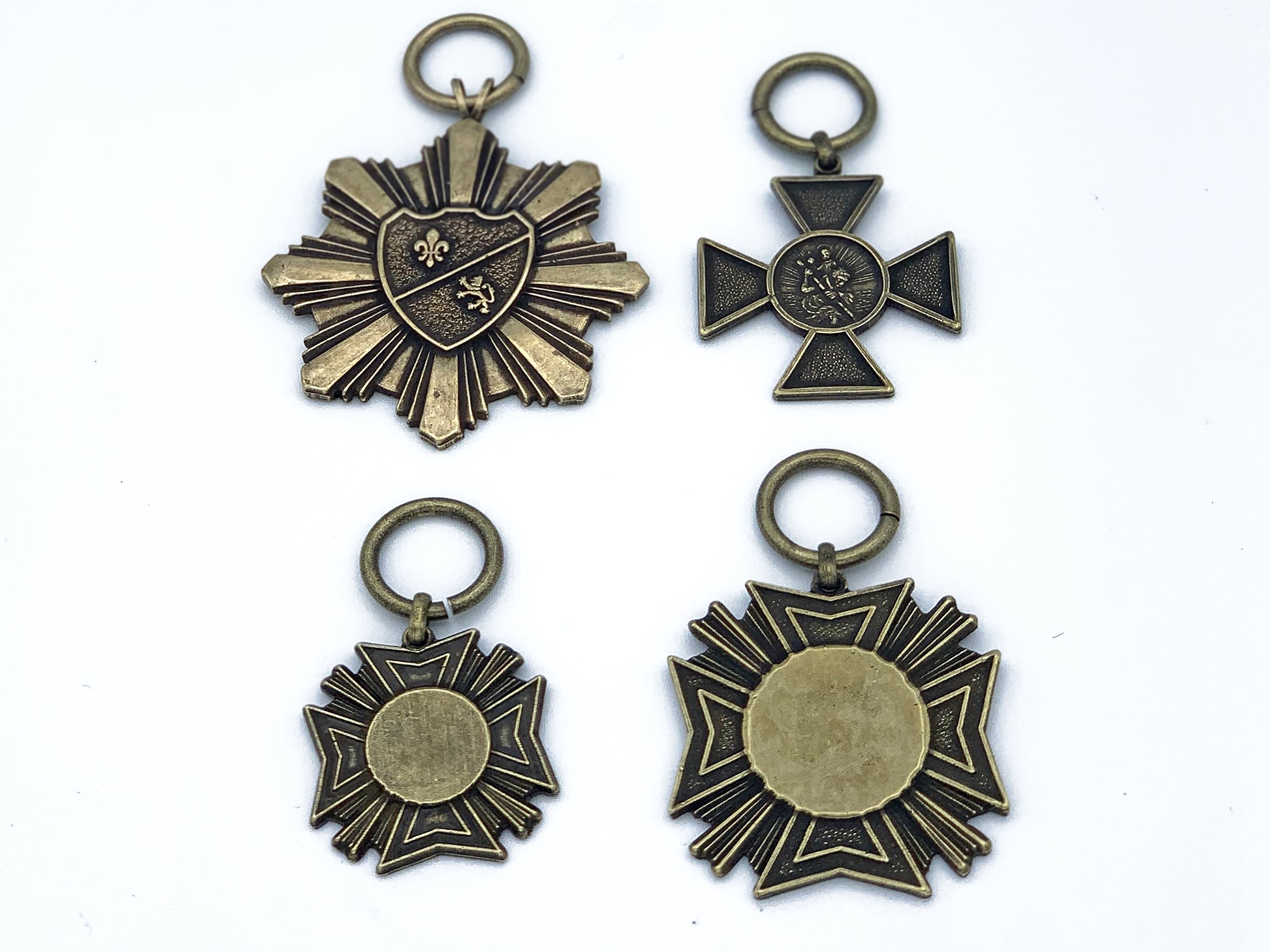 4 faux military metals in brass; large starburst, small iron cross, small and large Maltese cross