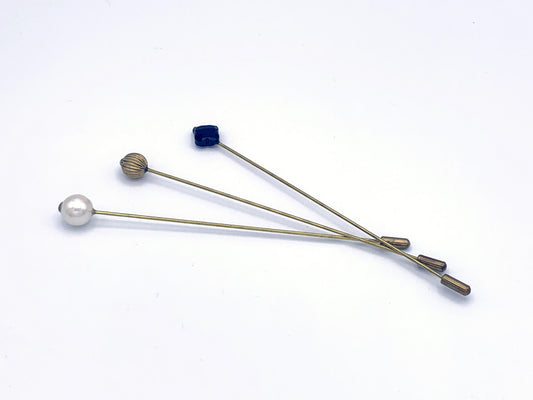 3 Long Brass hat pins with safety clasp. One has a black glass diamond finial, one has a corrugated brass spherical finial, and the final has a imitation pearl finial