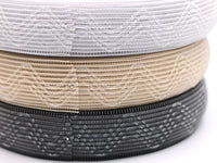 Close up photo of three rolls of silicone horsehair elastic. One in white, beige and black. semi-sheer elastic with silicone zigzag stripes. Gripper elastic. Wig band