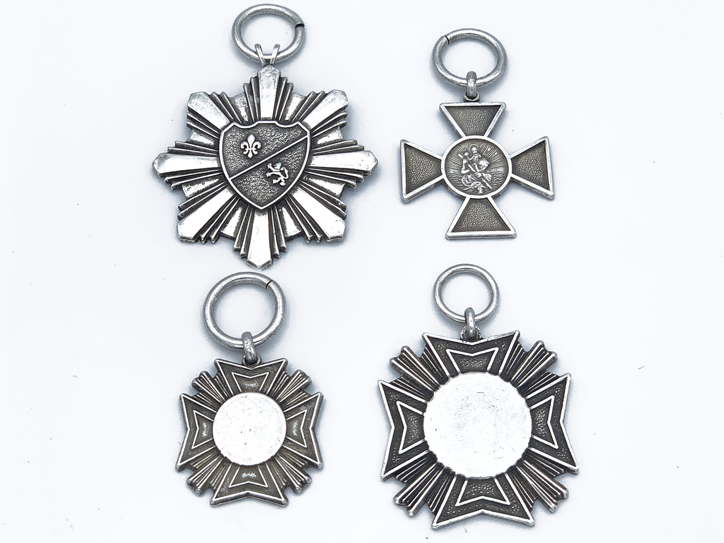 4 faux military medals in pewter; large starburst, Small iron cross, small Maltese cross and large Maltese cross