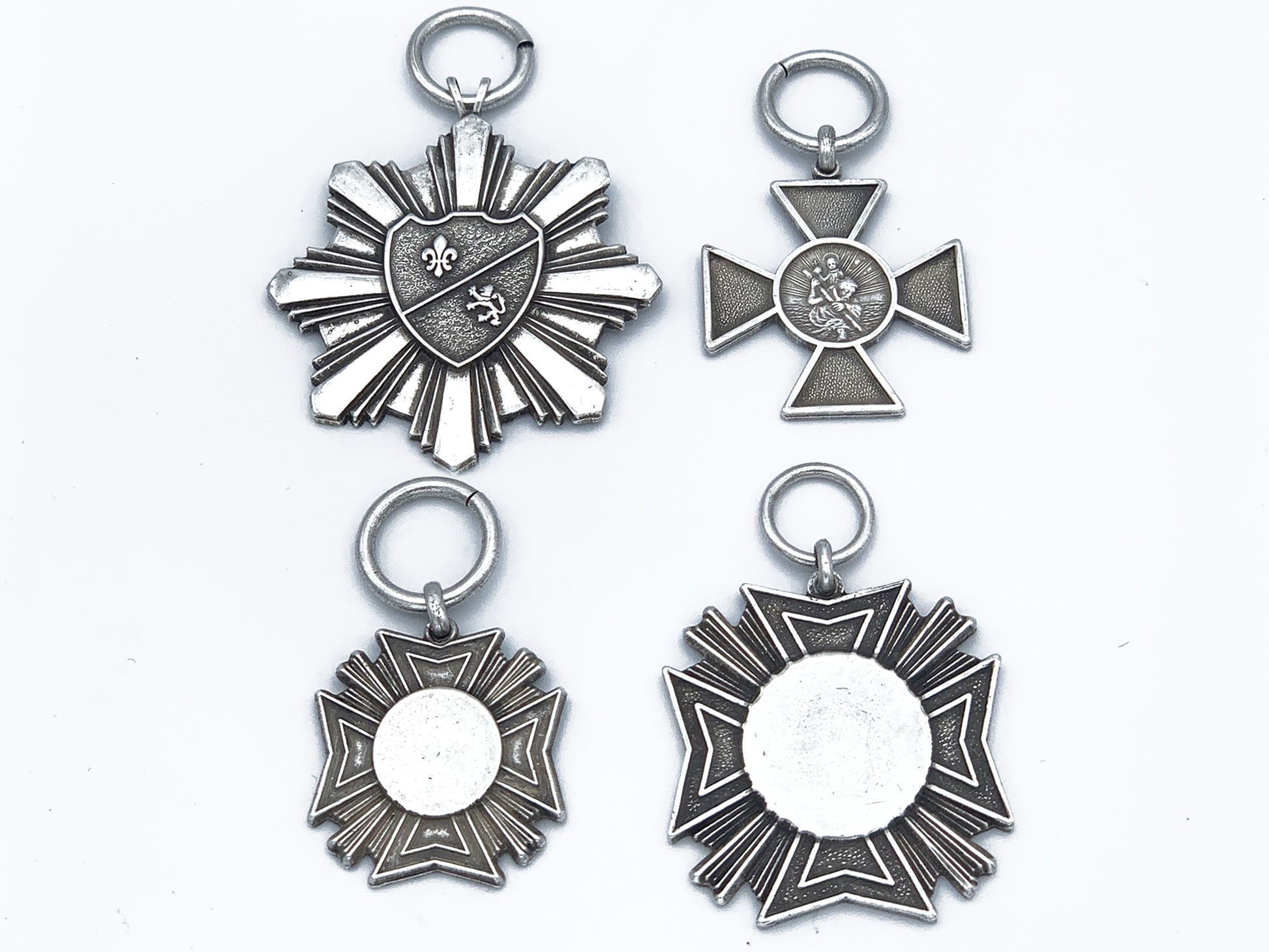 4 faux military medals in pewter; large starburst, Small iron cross, small Maltese cross and large Maltese cross