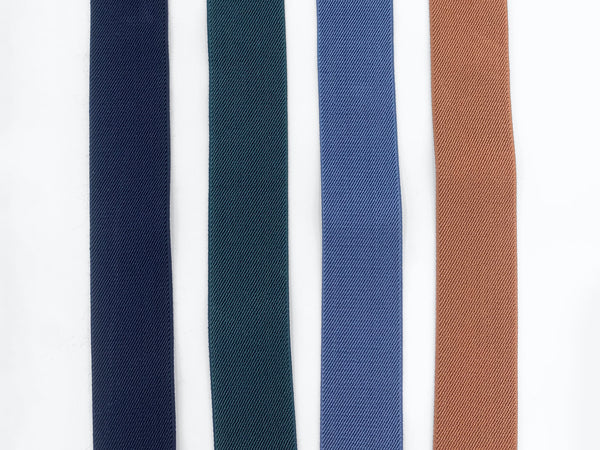 4 colors of elastic suspenders laid out next to each other; Black, Forest Green, Slate Blue and Camel